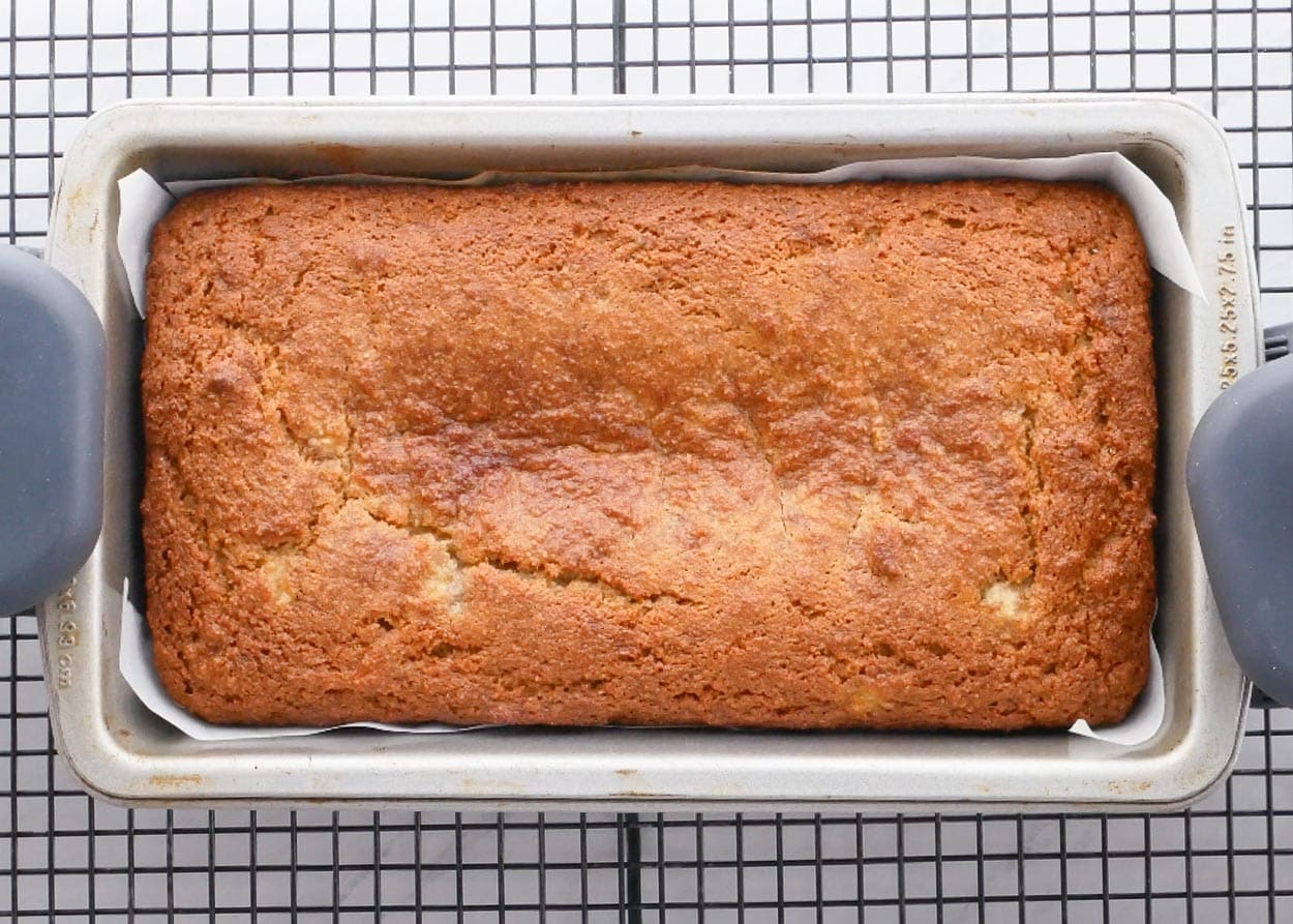 Baked almond flour banana bread in a loaf pan on cooling rack.