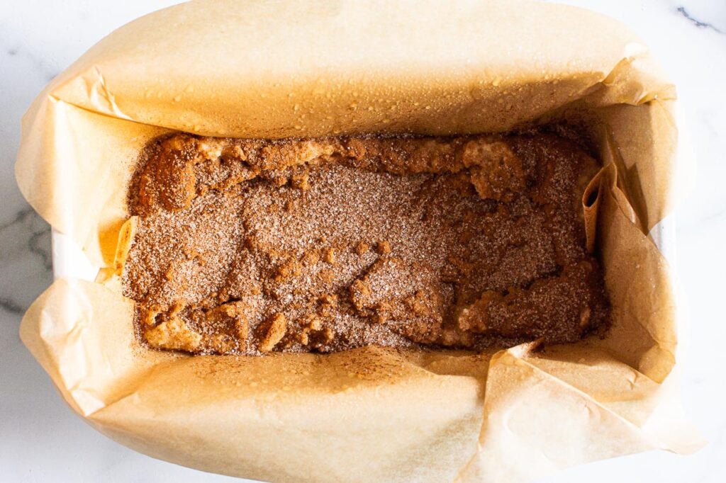 Almond flour cinnamon bread batter sprinkled with cinnamon sugar in a loaf pan. 