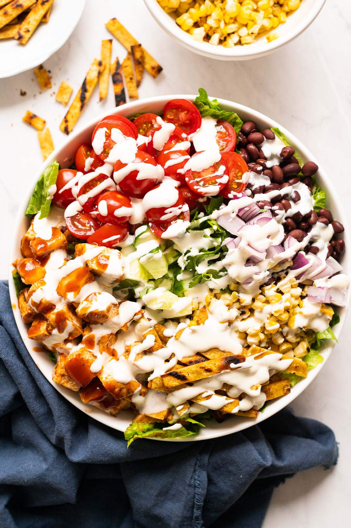 BBQ chicken salad drizzled with ranch dressing in a bowl.