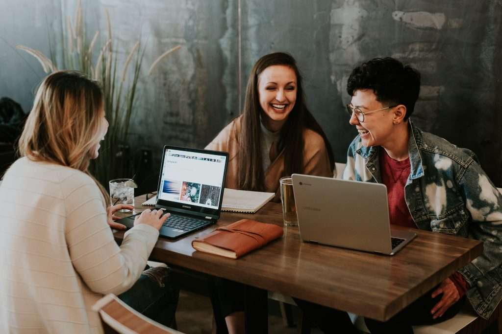 image of three people sitting at a table working happily thanks to team events