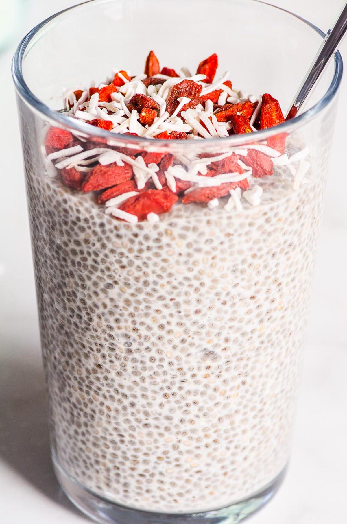 Overnight chia pudding in glass with chocolate chips, goji berries and coconut flakes.