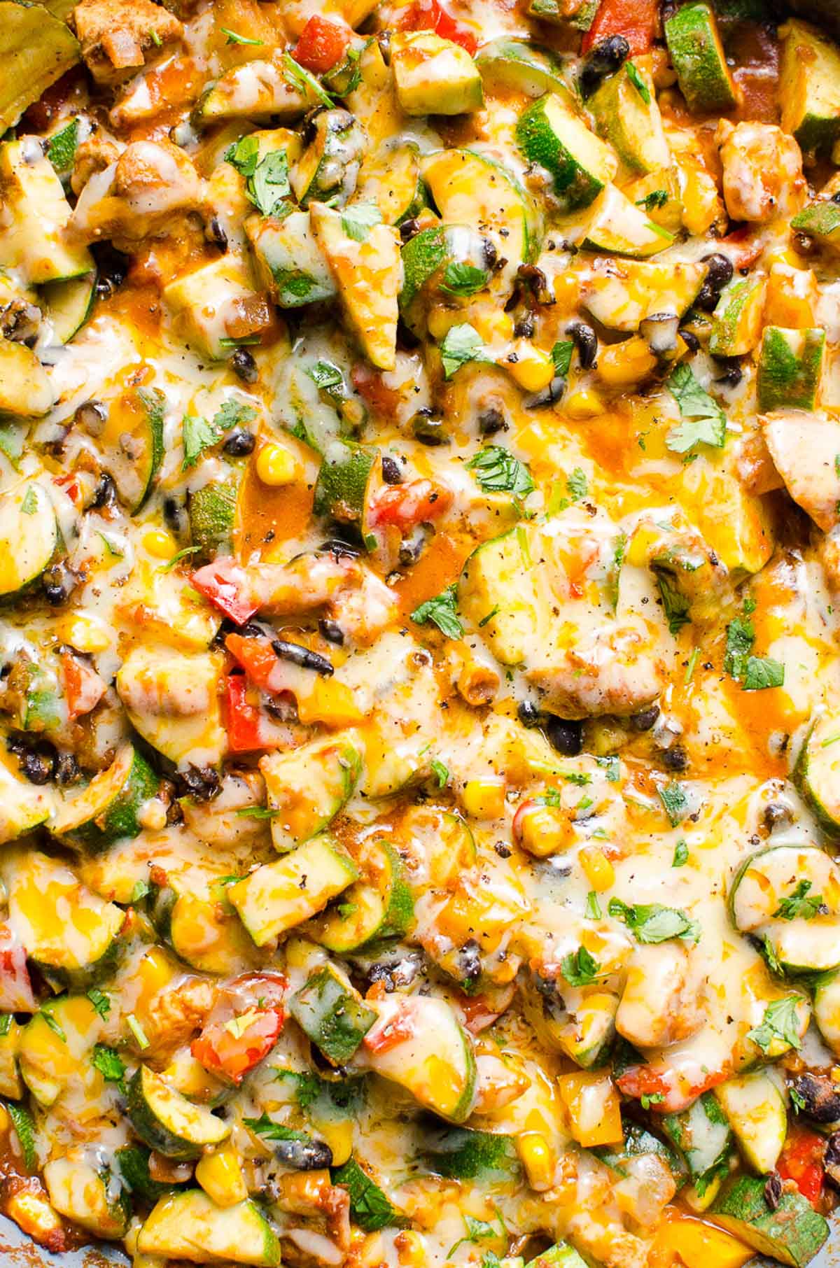Closeup of Tex Mex chicken and zucchini recipe with corn and black beans topped with melted cheese.