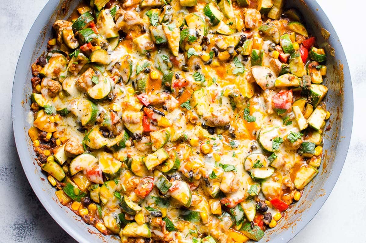 Chicken and zucchini recipe with melted cheese and cilantro in a skillet.
