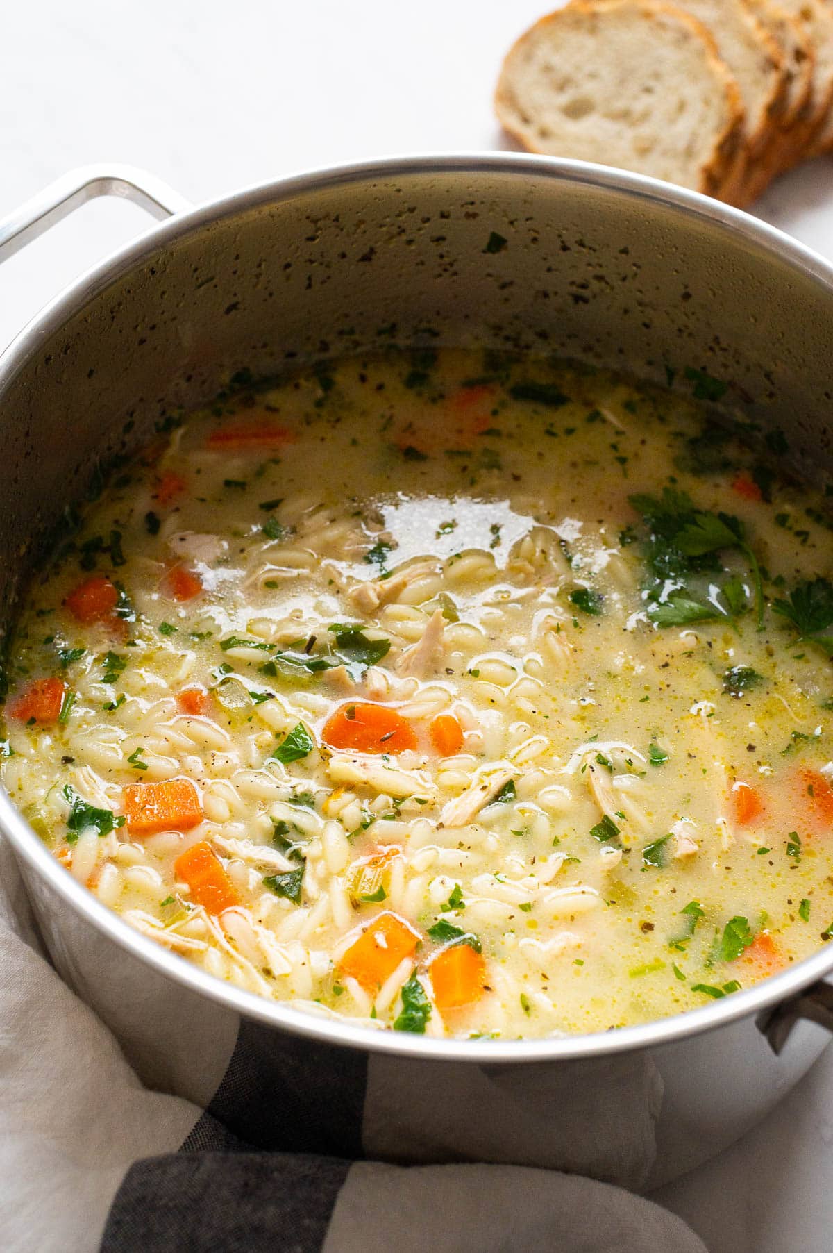 Chicken orzo soup  in a metal pot.