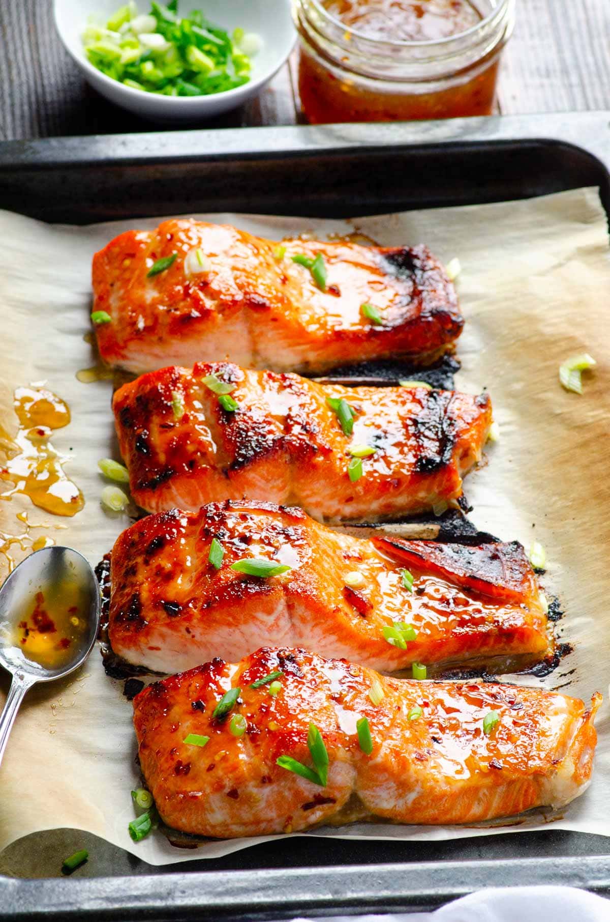 Broiled thai salmon fillets on baking sheet lined with parchment.