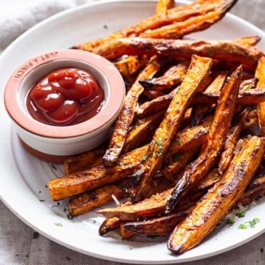 Air fryer sweet potato fries on a plate with bowl of ketchup.