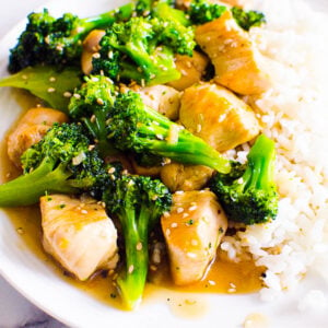 Chicken and broccoli stir fry garnished with sesame seeds and served with rice.