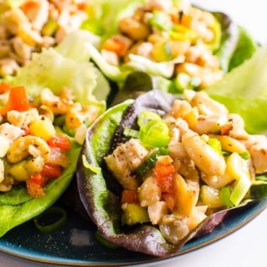 Healthy chicken lettuce wraps with cashews and green onions served on a plate.