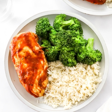 BBQ chicken breast with rice and broccoli on a plate.