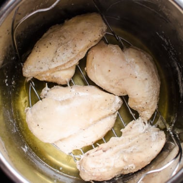 Four Instant Pot frozen chicken breasts in pressure cooker pot..