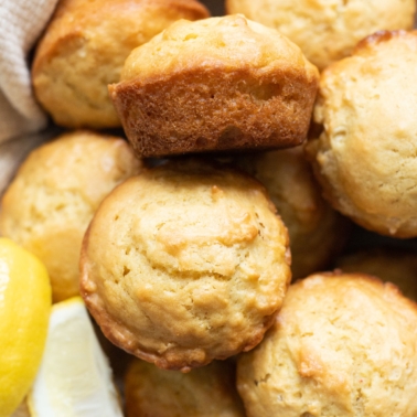 Lemon muffins served in a basket with a few slices of fresh lemon.