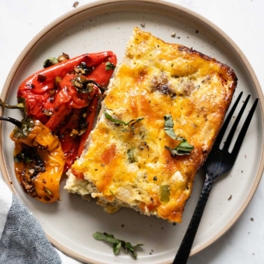 A slice of low carb breakfast casserole with roasted mini peppers on a plate with a fork.