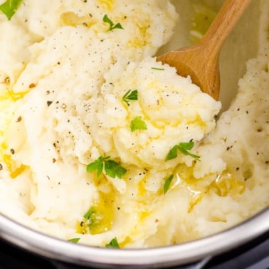 Mashed potatoes in Instant Pot garnished with parsley and pepper.