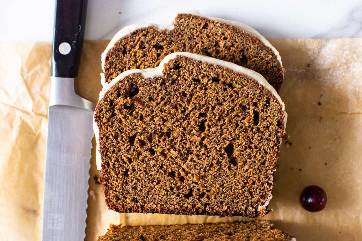 Two slices of healthy gingerbread loaf with icing on parchment paper.