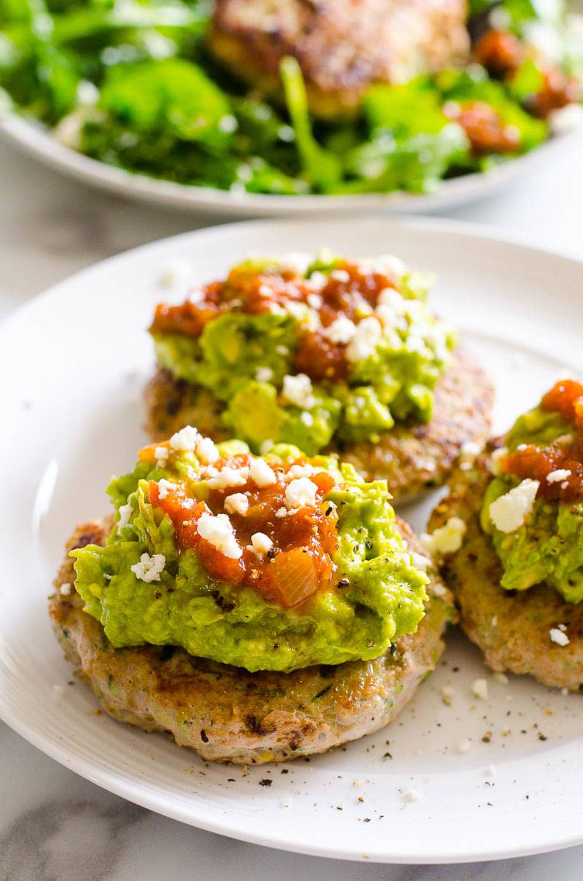 Healthy turkey burgers topped with guacamole, salsa and feta.