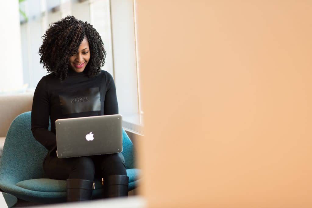 african american woman in a black turtleneck writing an event sponsorship letter on a macbook