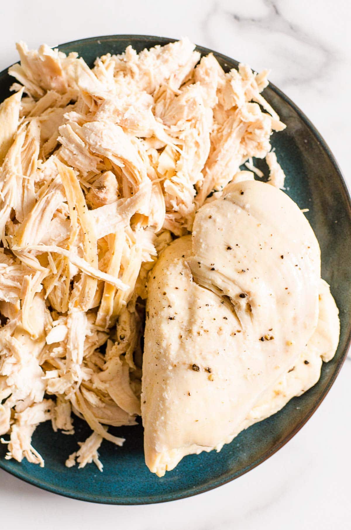 Instant Pot chicken breast and shredded chicken on a plate.