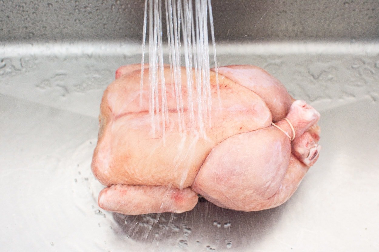 Rinsing frozen chicken in a sink.