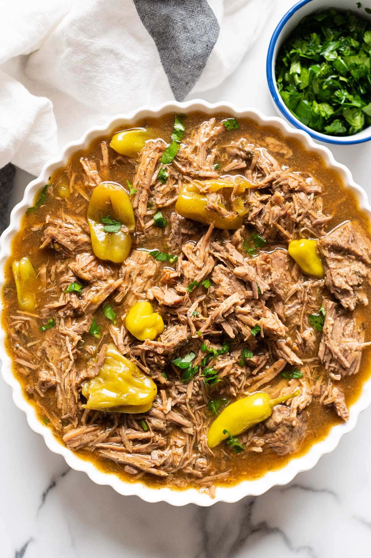 Instant Pot Mississippi pot roast with peperoncini peppers and parsley in a bowl.