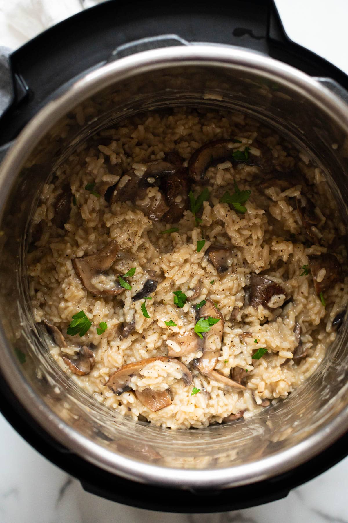 Instant Pot mushroom risotto garnished with parsley in a pressure cooker.