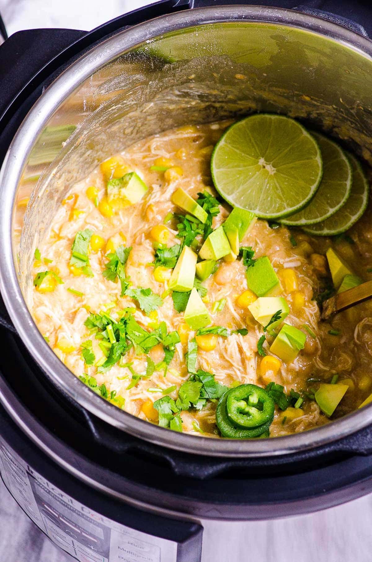 Instant Pot white chicken chili in the pressure cooker garnished with lime.