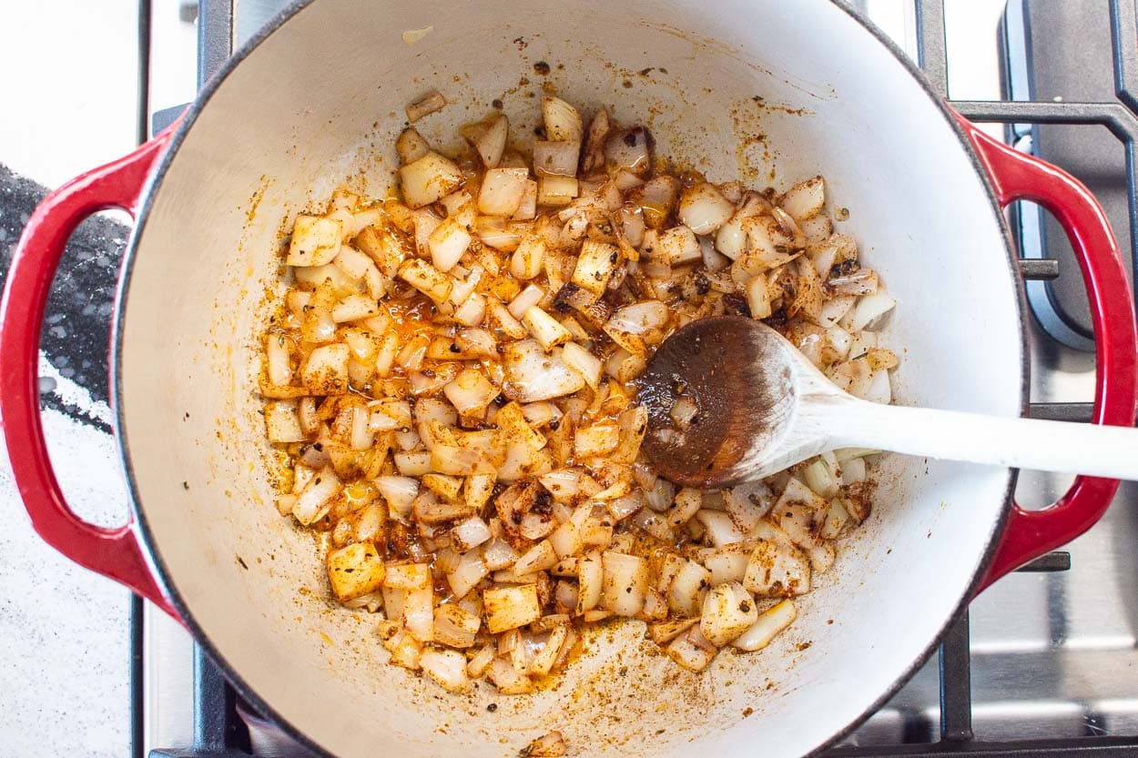 Sautéing onion and spices in pot on stovetop.